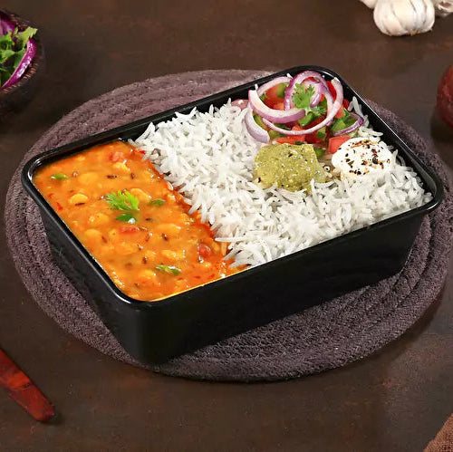 Black rectangular container with food on a brown surface