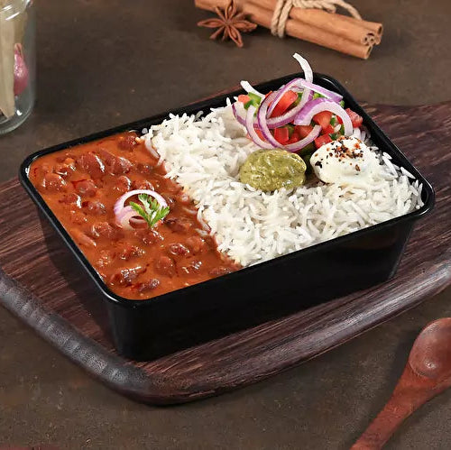 Dish with rice, beans, and vegetables on a wooden board with spices and a bottle of oil.